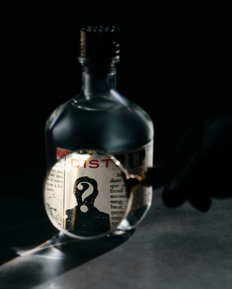 Loupe zoomant sur l'étiquette du gin distillé Hold Up dans une atmosphère sombre